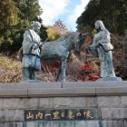 城山公園（旧二の丸）の山内一豊と妻の像越しに仰ぐ天守