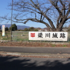 梁川城の大看板、奥の草原は元本丸、小学校保育園は撤去済み