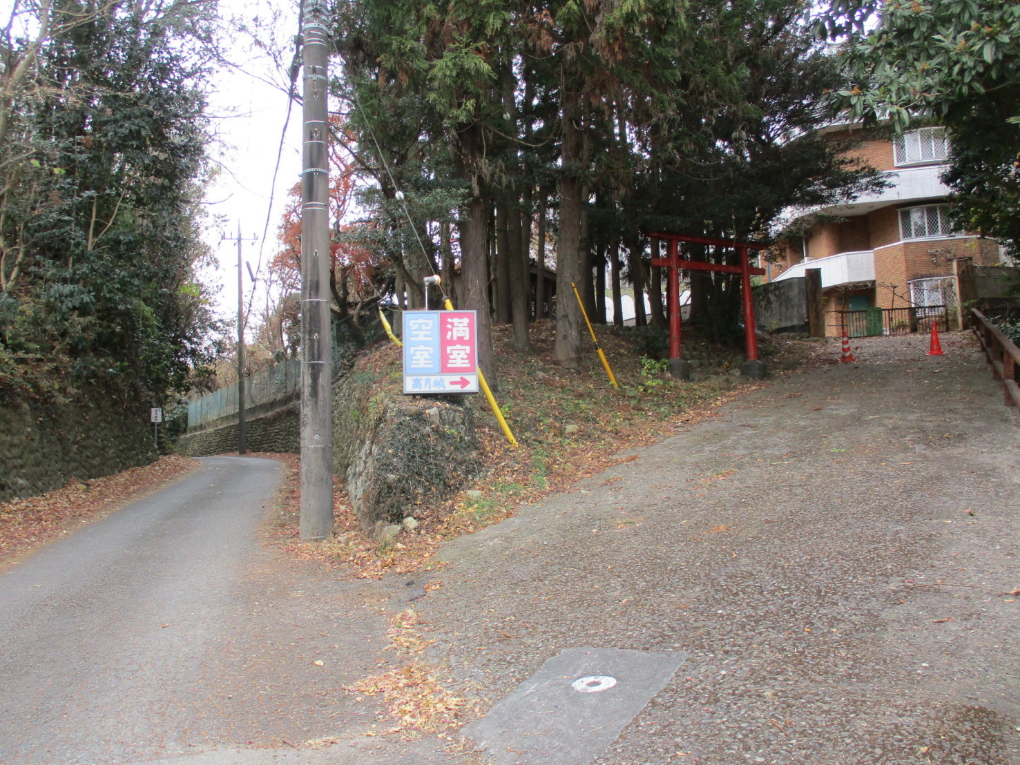 右手にホテル、前に神社、道路奥左が入口