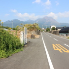 石碑を入れて雲仙普賢岳を遠望する、手前の路側帯に路駐