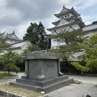 戸田氏鉄公騎馬像と天守、左は戌亥櫓