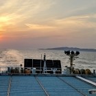 ④	帰りの博多行のフェリーから見た夕陽と壱岐島（金田城）