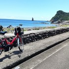 ④	海岸沿いを爽快に走る（後方は立神岩）